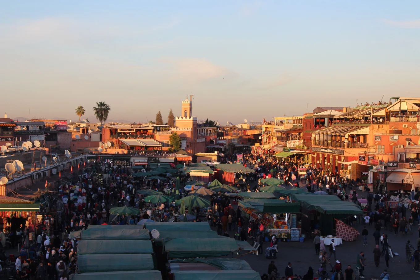 Busy market square with people, stalls, buildings.